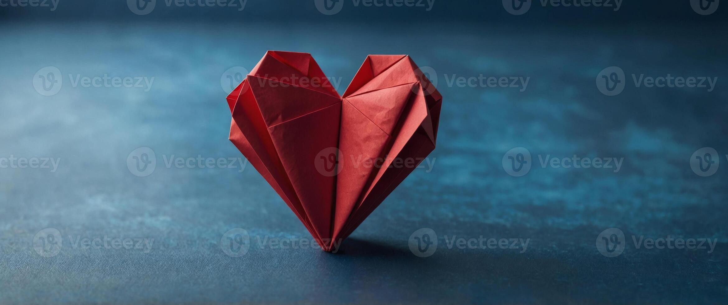 Red paper heart folded into origami shape on blue background. photo