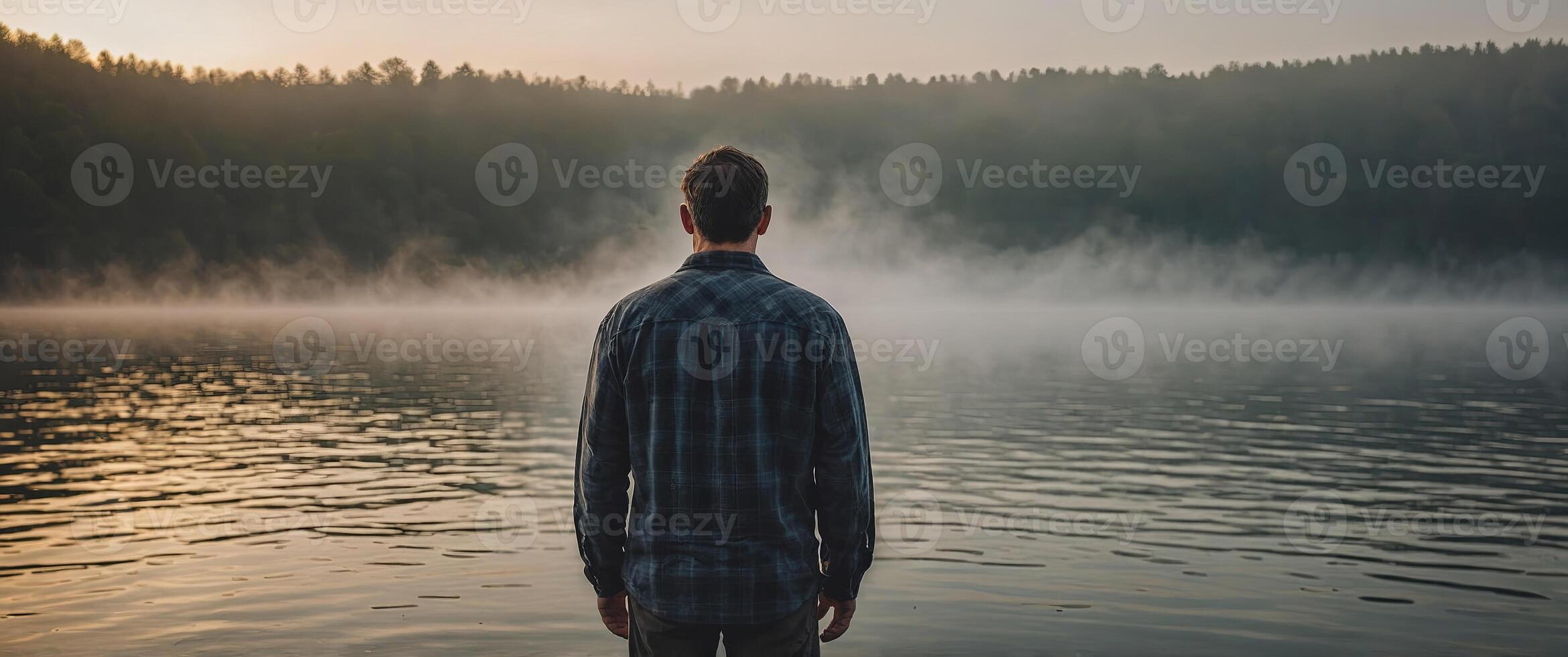 A man standing in front of a foggy lake preparing for his morning routine with a round of deep breaths. photo
