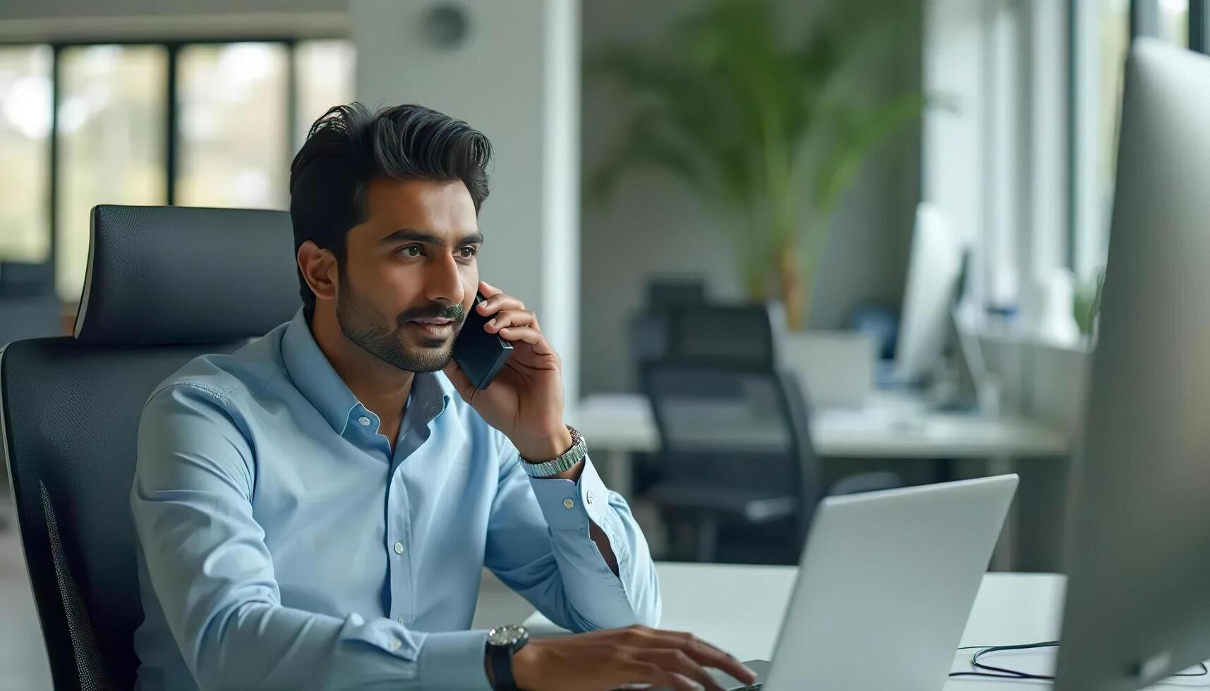 a man sitting at a desk with a laptop and talking on the phone photo