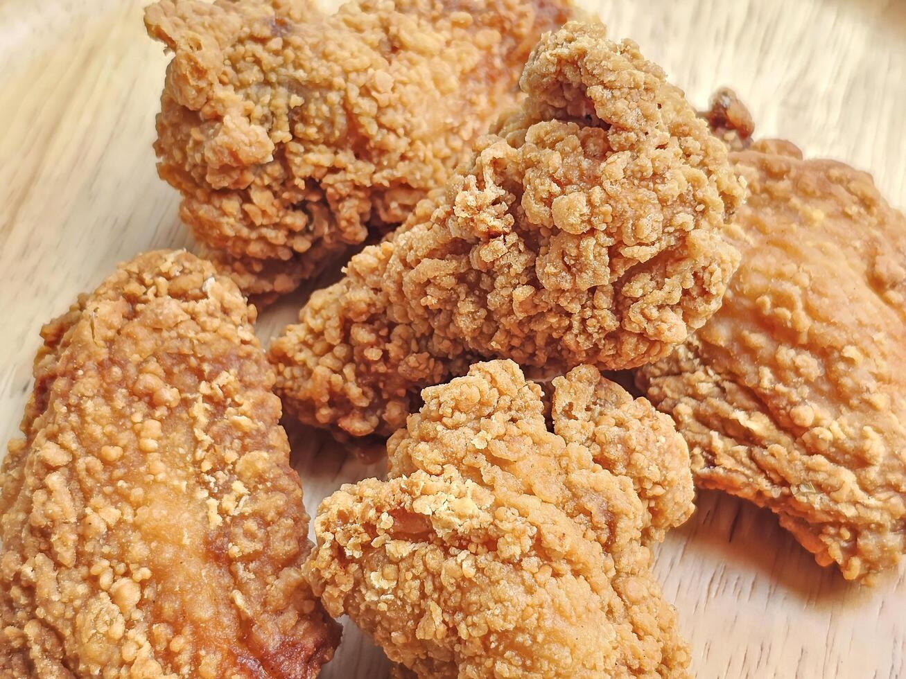 Close up, group of fried chicken wings arranged on wooden plate photo