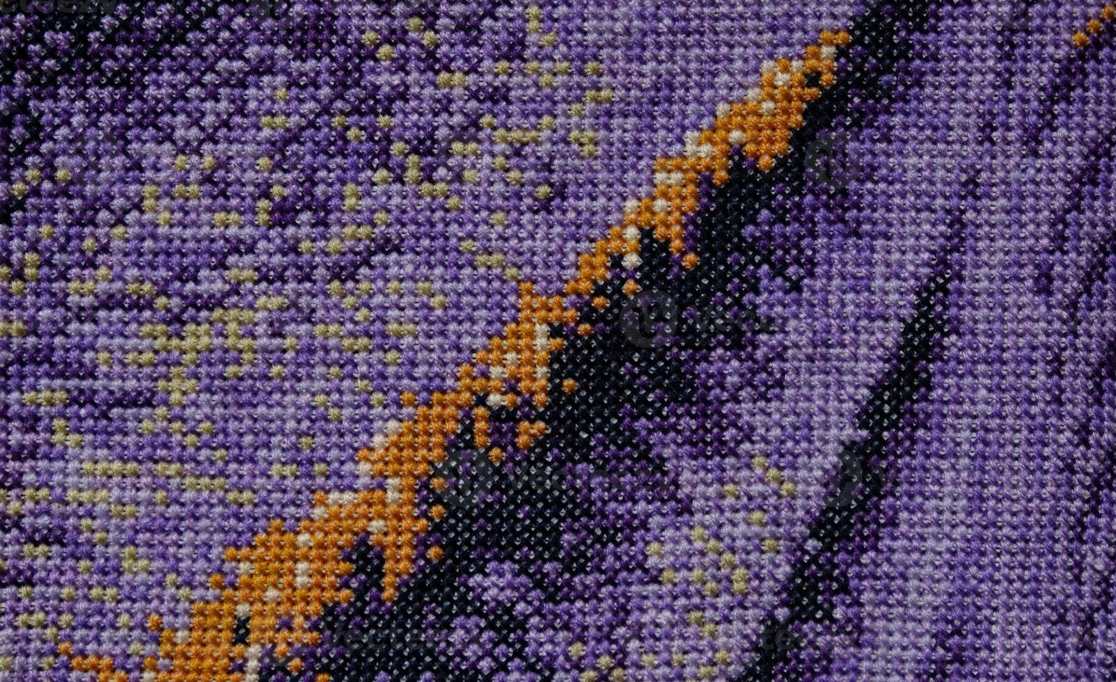 Purple, violet and brown close-up cross stitch background. Abstract Embroidered handmade Pattern. Needlework and DIY concept. Top view, macro, flat lay, mockup. photo