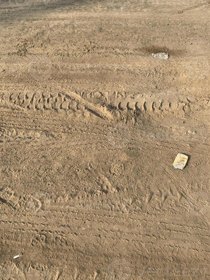 Highway construction track featuring a dirt road with truck wheel marks and workers' shoe prints. Ideal for construction and infrastructure visuals. photo