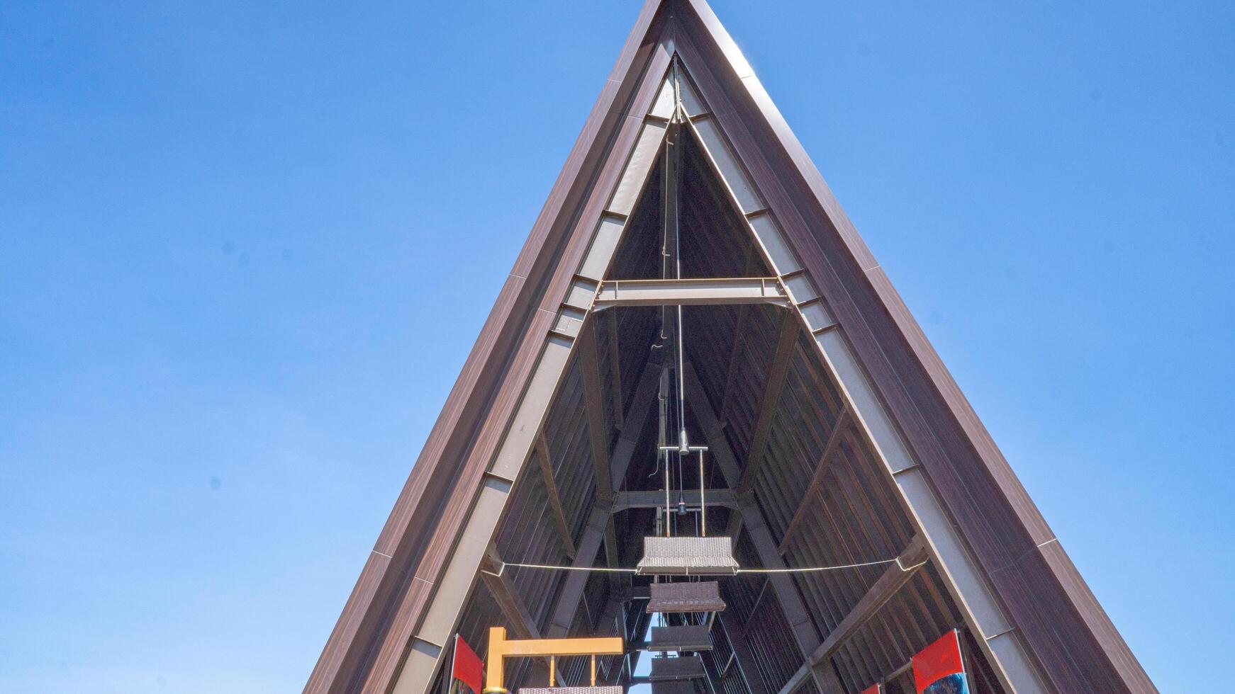 Metal Structure Against the Sky. A low angle view of a large metal triangular structure against a bright blue sky. photo