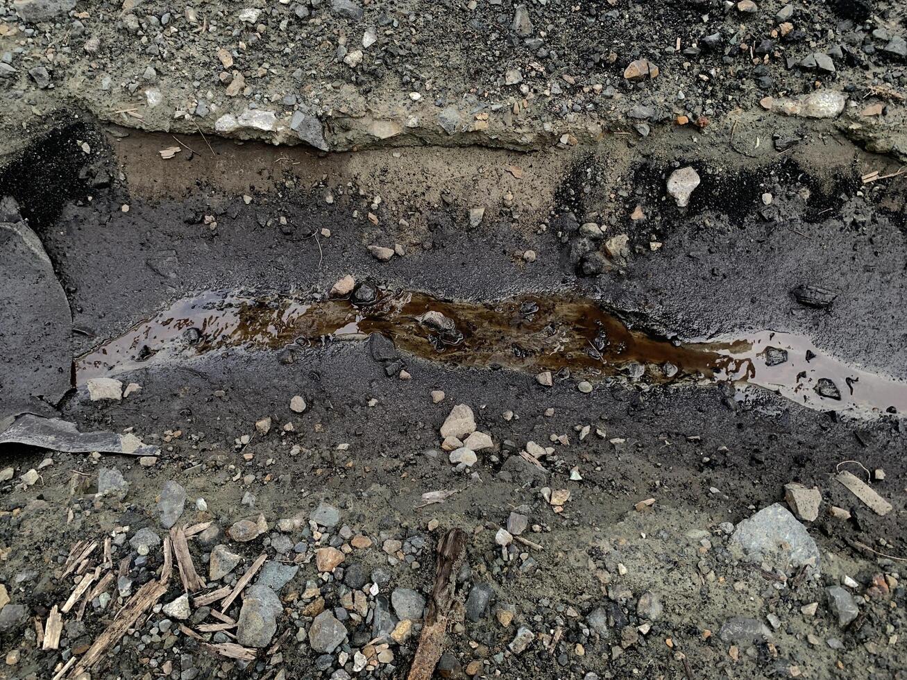 contaminated water with coal on coal yard area. A small stream of water flows through a gravel path, creating a natural drainage channel. photo