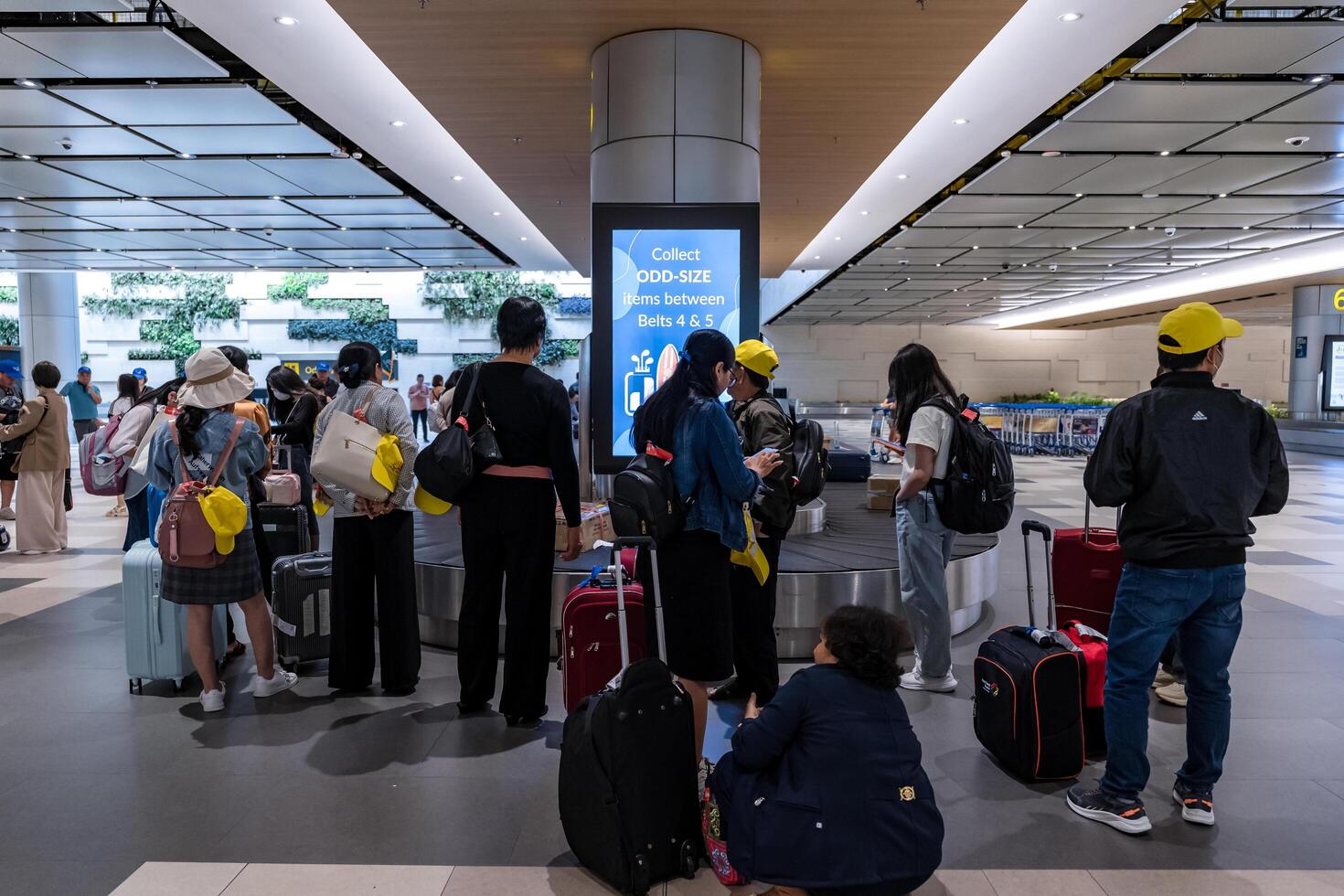 Passengers collect their suitcases from the airport conveyor belt, ready for their journey at Terminal 3, Changi Airport, Singapore photo