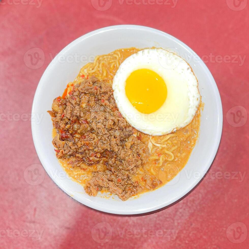 top view spicy curry noodle with beef and sunny side up egg topping on red background photo