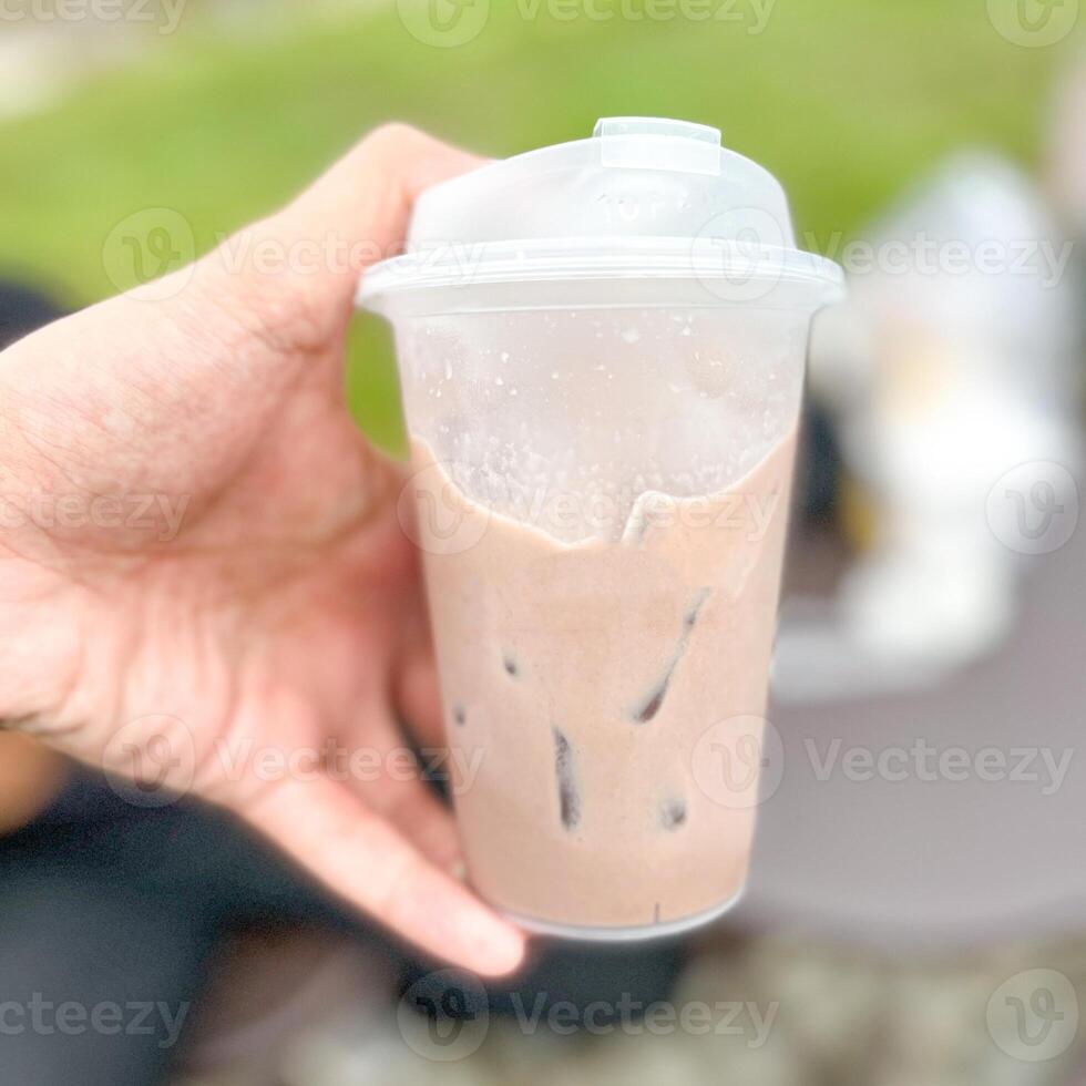 Male Hand Holding Cup of Sweet Chocolate Milk with blur background photo