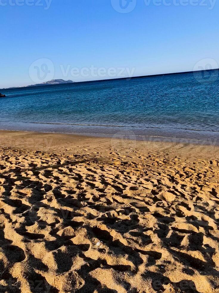 A sunny summer beach with golden sands sparkling under the warm sun, while the gentle waves of the sea play a soothing melody. photo