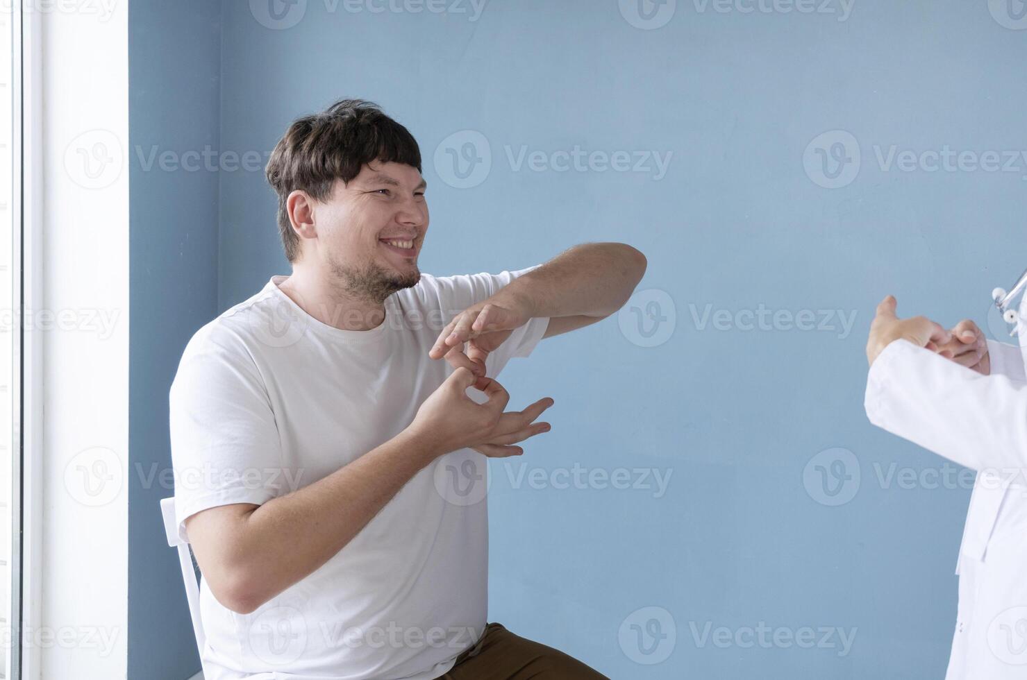 young male patient testing hearing aid in clinic exam room, female doctor helping photo