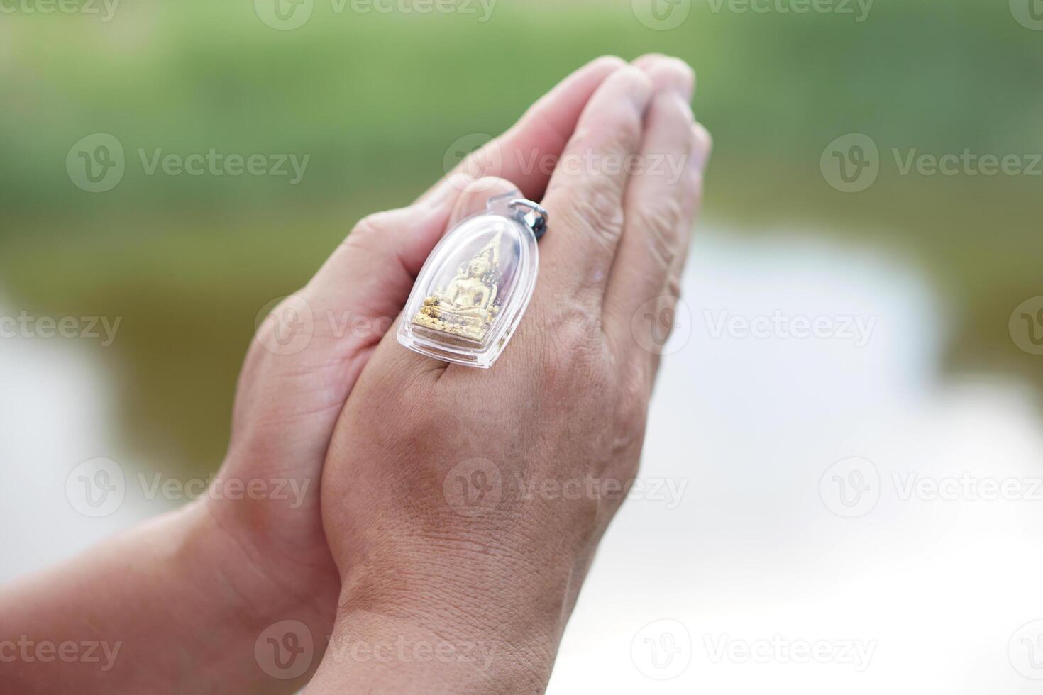 Close up hands holds buddha amulet and pray. Concept, faith and belief of Buddhist for holy to protect from dangers, bring good luck, business prosperity and wealth. Collecting amulet. photo