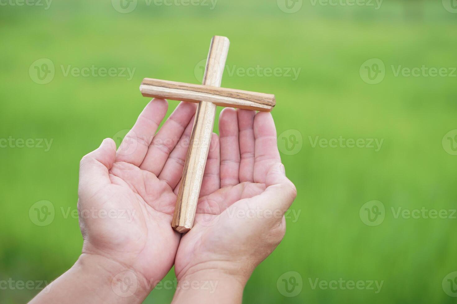 Closeup wooden cross on hands. Concept, Christian worship. Faith, forgiveness, belief, love, hope, peace and happiness. Crucifix, religious symbol of Christianity. photo