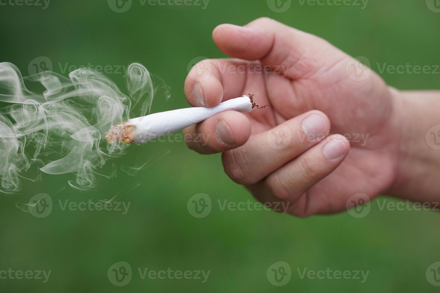 Close up hand holds homemade cigarette for smoking. Concept, smoking is bad for health. Private favorite for relaxation but can cause health problems respiratory disease and addict. photo