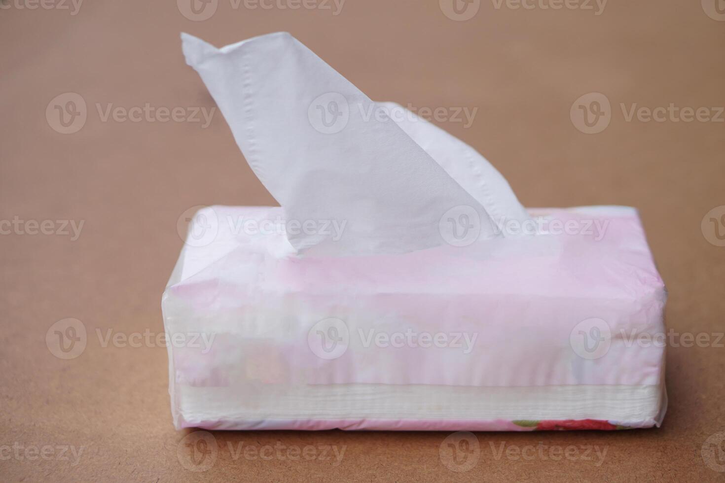 Sheet tissue paper package, on brown background. Concept, item for cleaning, wiping or absorbing dirt from face, skin or other purposes for hygienic and sanitary daily life. photo