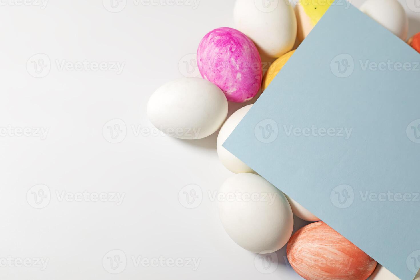 Colorful easter eggs with blue paper card on white background. photo
