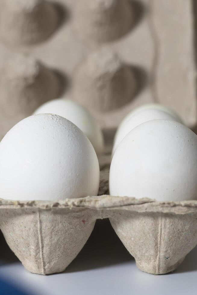 White eggs in a carton box on a white background. Selective focus. photo