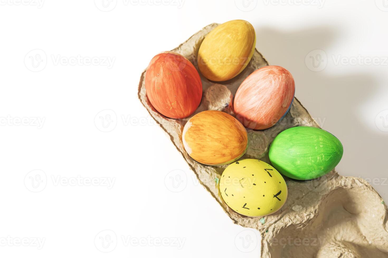 Colorful easter eggs in a cardboard box on a white background with copy space. photo