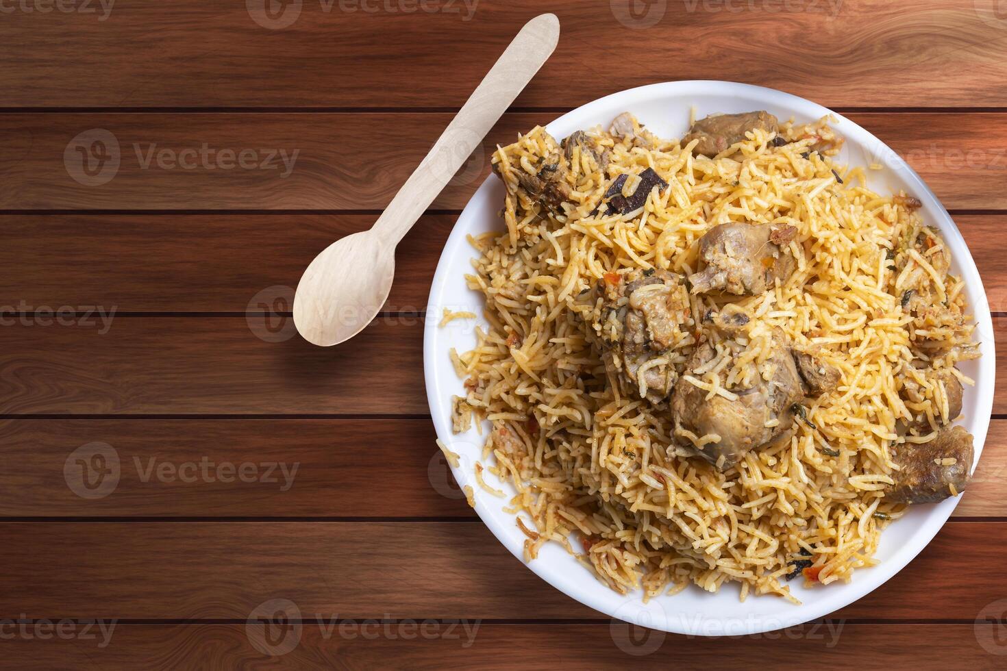 Indian famous food delicious mutton biryani on white plate on wooden table. Top view photo