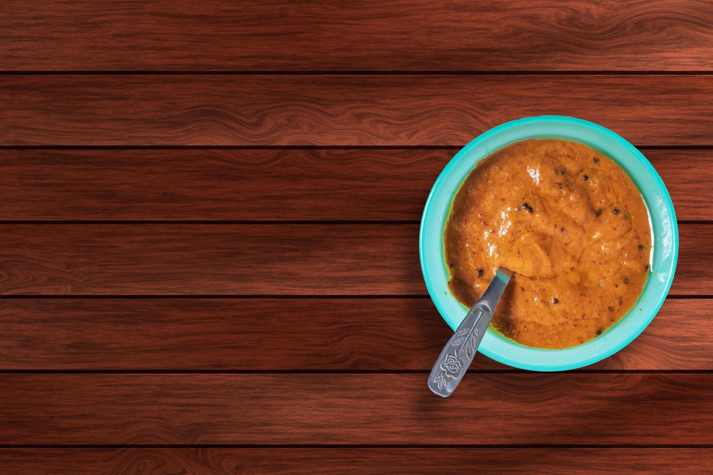 Onion chutney in a blue bowl with spoon on a wooden table. photo