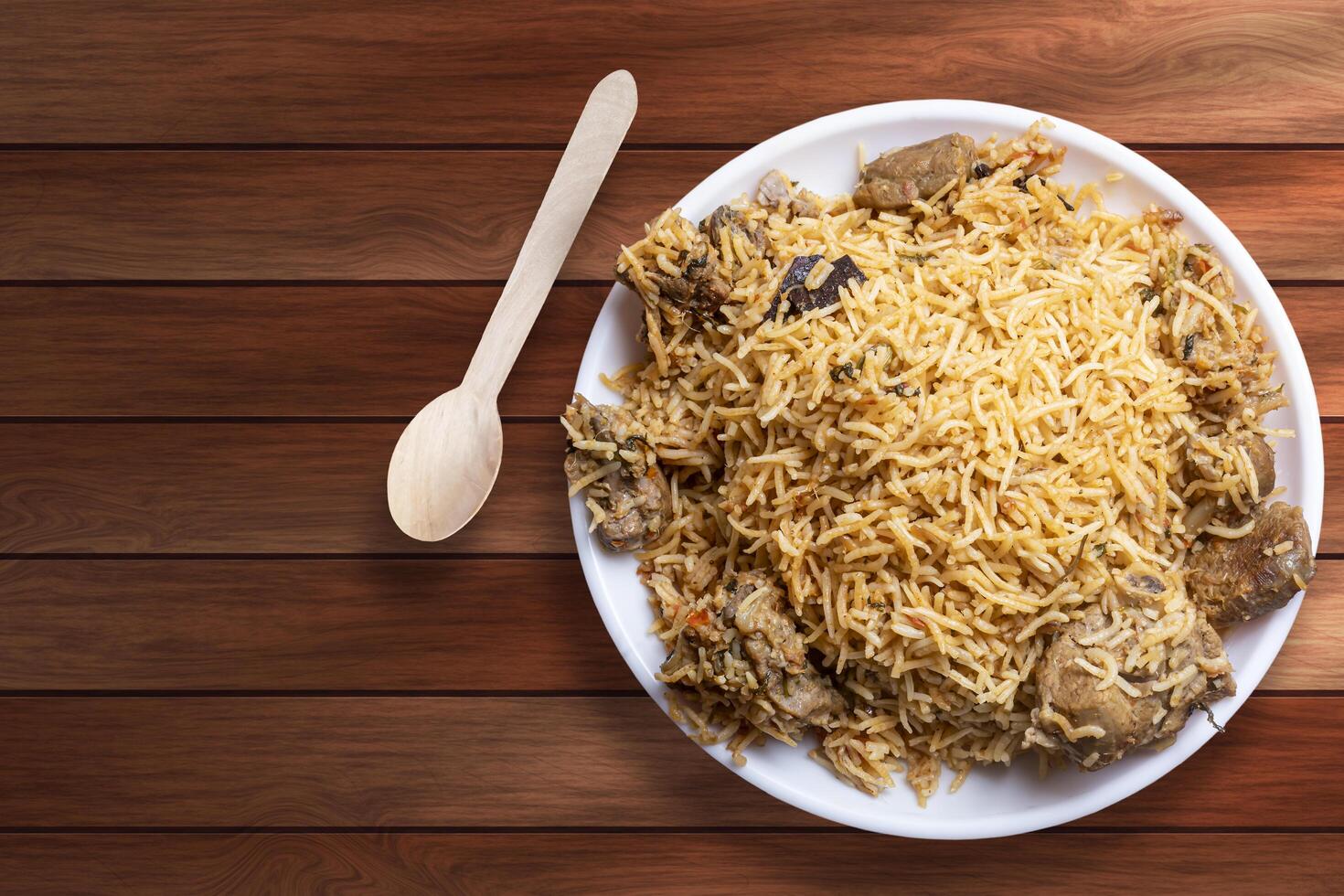 Indian famous food delicious mutton biryani on white plate on wooden table. photo