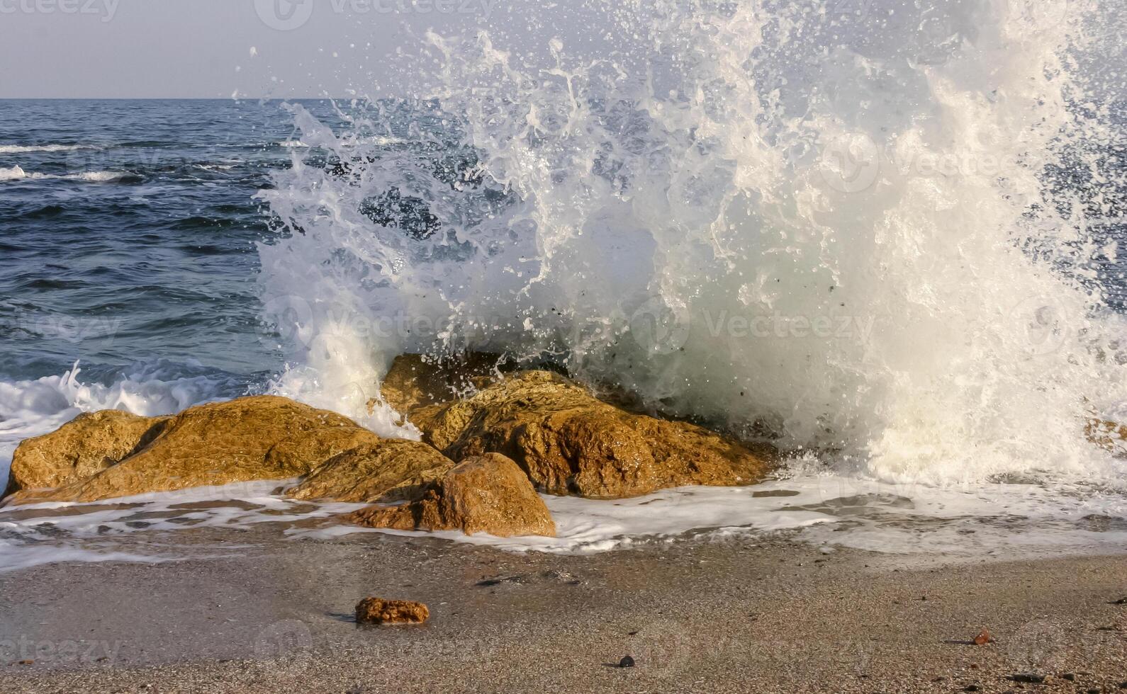 Waves break on a stone and white splashes of water fly into the air, the Black Sea photo