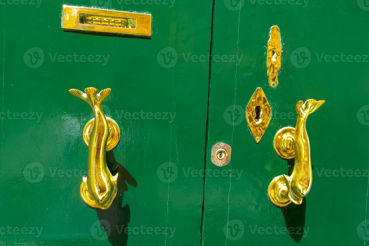 Traditional handle and doorknocker made of brass in the form of fish on the doors of old houses in Malta photo