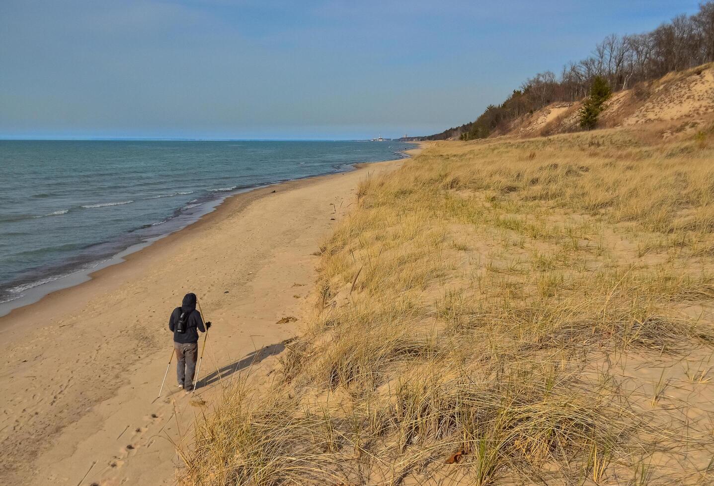 USA, Ohio - April 26, 2018 Sand dunes near the shore of a large lake, a tourist with ski patches walks along the shore. photo