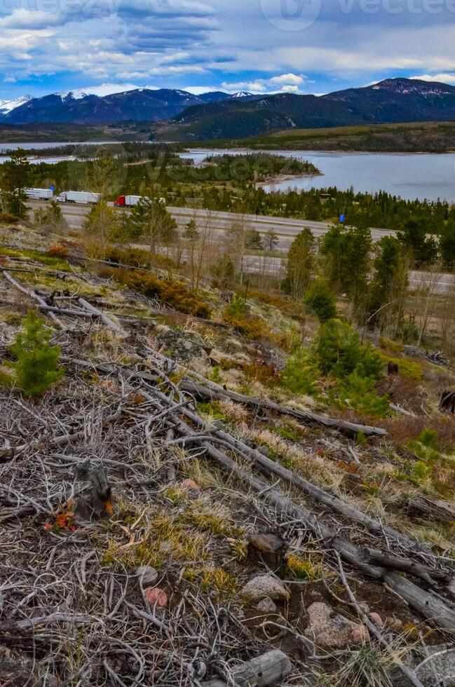 Felled trees in the hills near a mountain lake against the backdrop of snow-capped mountains in Utah, US photo