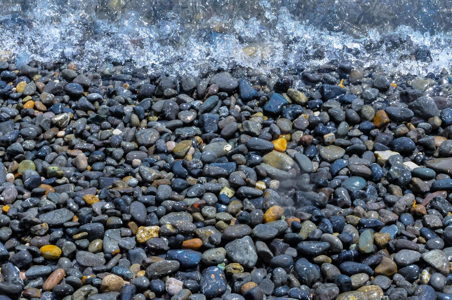 Kara-Dag, a round sea-rolled pebble from a volcanic rock on a pebble beach, Crimea photo