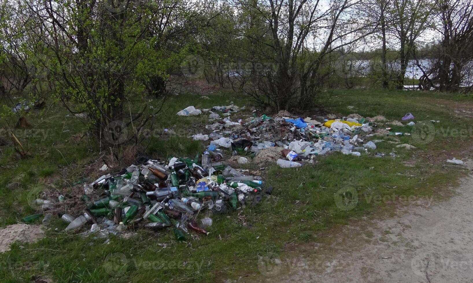 Environmental problem, pollution, polyethylene, polypropylene, mud, waste, scrap metal, bottles, garbage dump on the river bank photo
