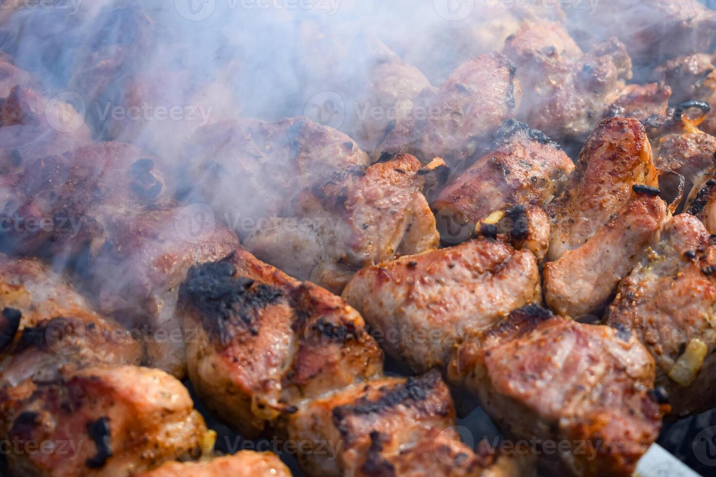 Pork meat is fried on smoking coals in the grill photo