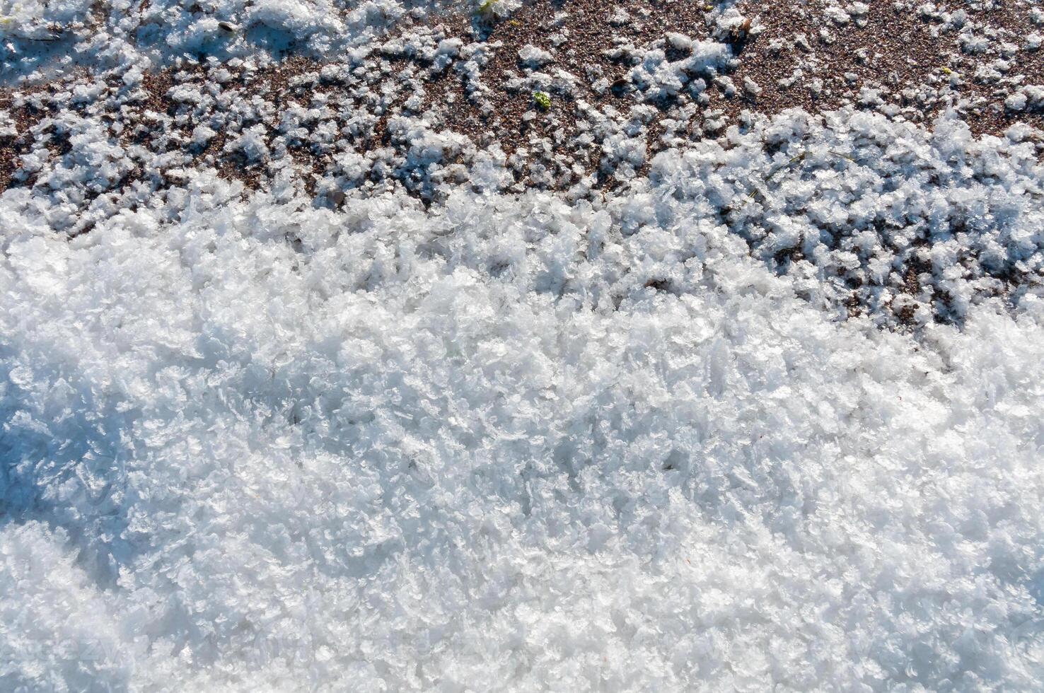 Weathered ice and frozen snow in the form of needle crystals on the bank of the Tiligul Estuary on a sunny day photo