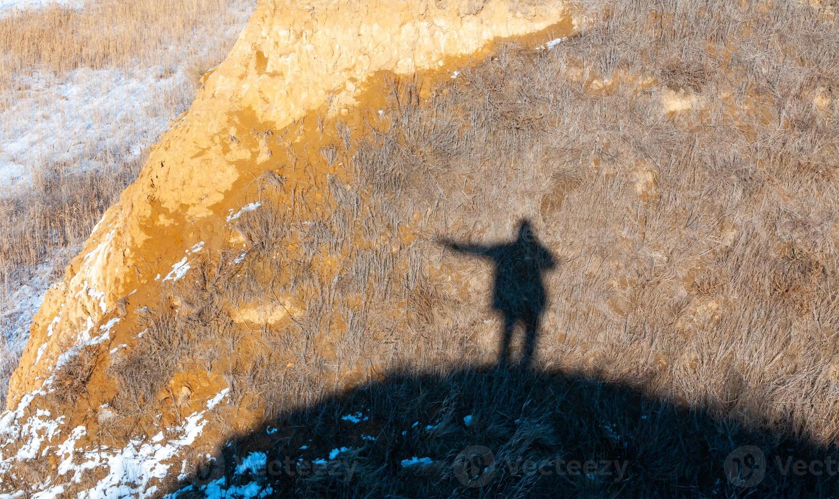 Black shadow, silhouette of a man with a raised hand on the shore of the estuary in winter photo