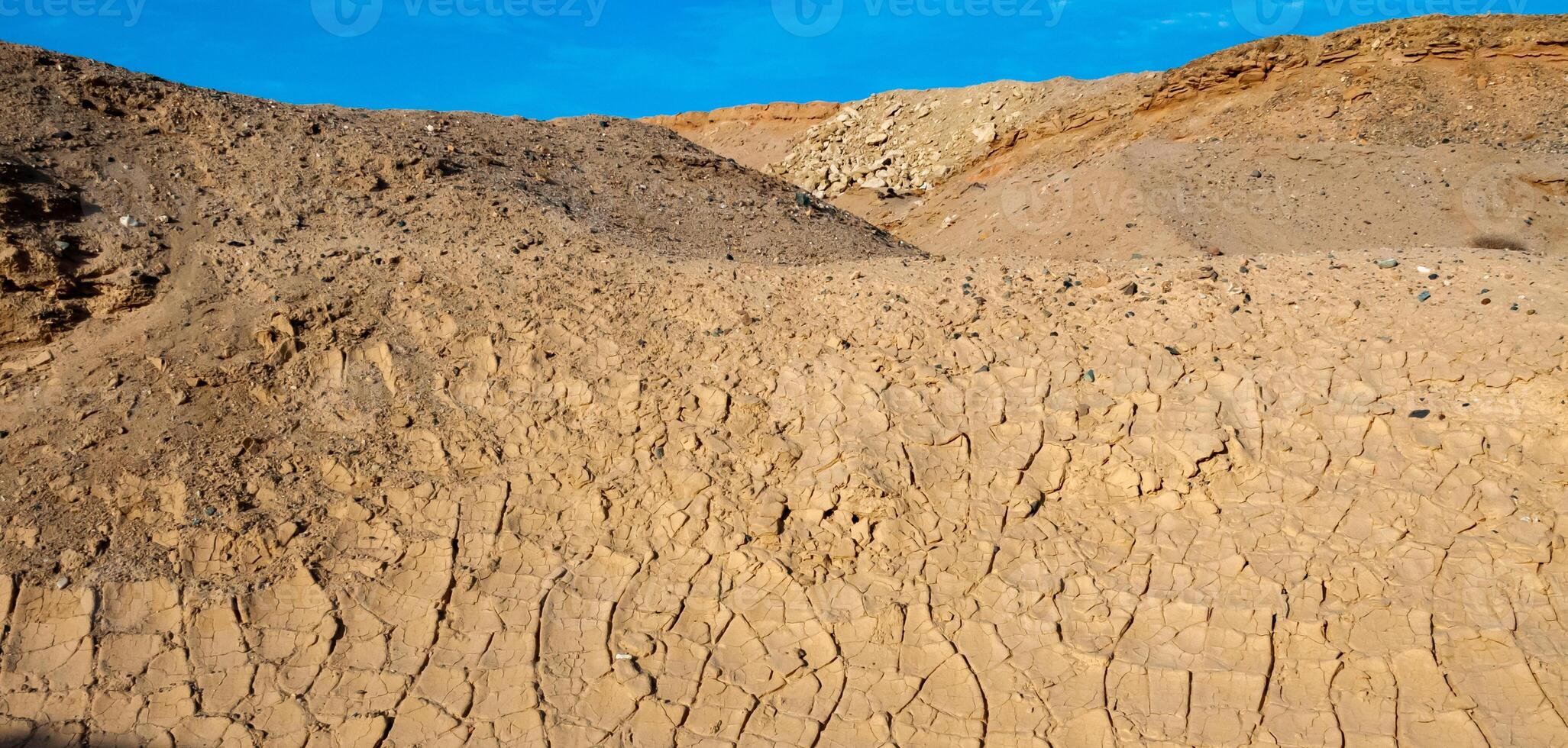 Dry cracked red clay in the desert in the bed of a dried up water stream, Egypt photo