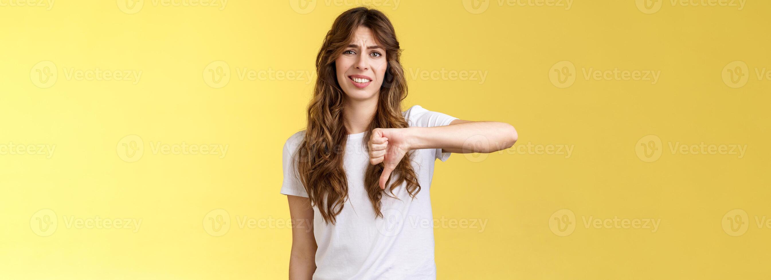 So lame you loser. Ignorant snobbish good-looking woman give own judgement negative opinion disagree grimacing cringe dislike show thumb down disappointed unimpressed yellow background photo