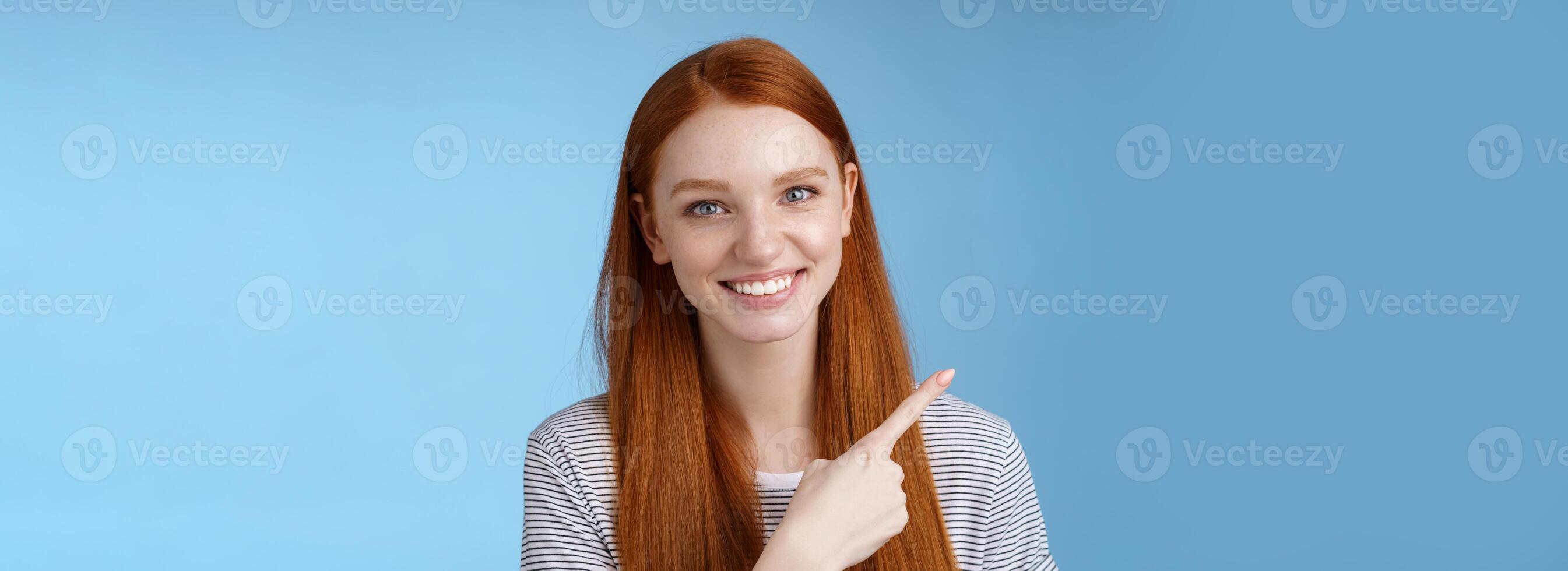 Close-up attractive gentle tender friendly-looking smiling redhead woman show place pointing upper left corner index finger grinning helpful giving choice help find store, standing blue background photo