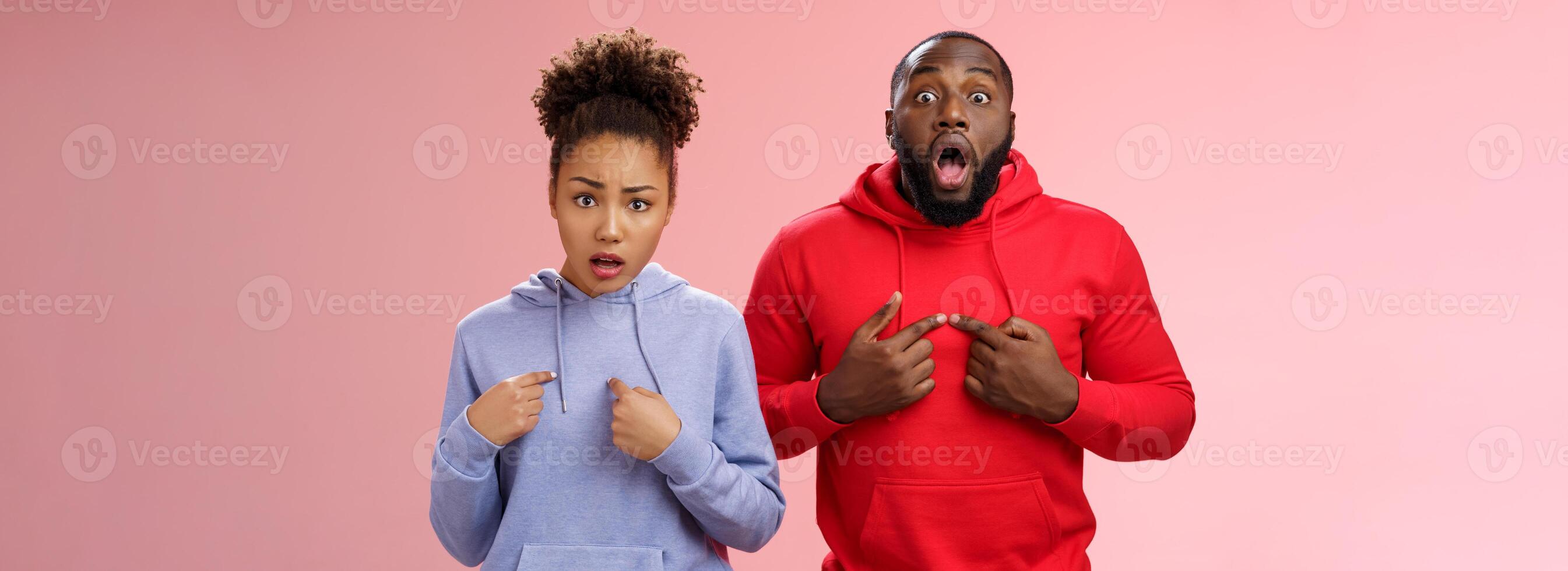 Why us. Shocked disturbed complaining two african american brother sister pointing chest index fingers frowning bothered upset man widen eyes surprised woman frowning sorrow, standing pink wall photo