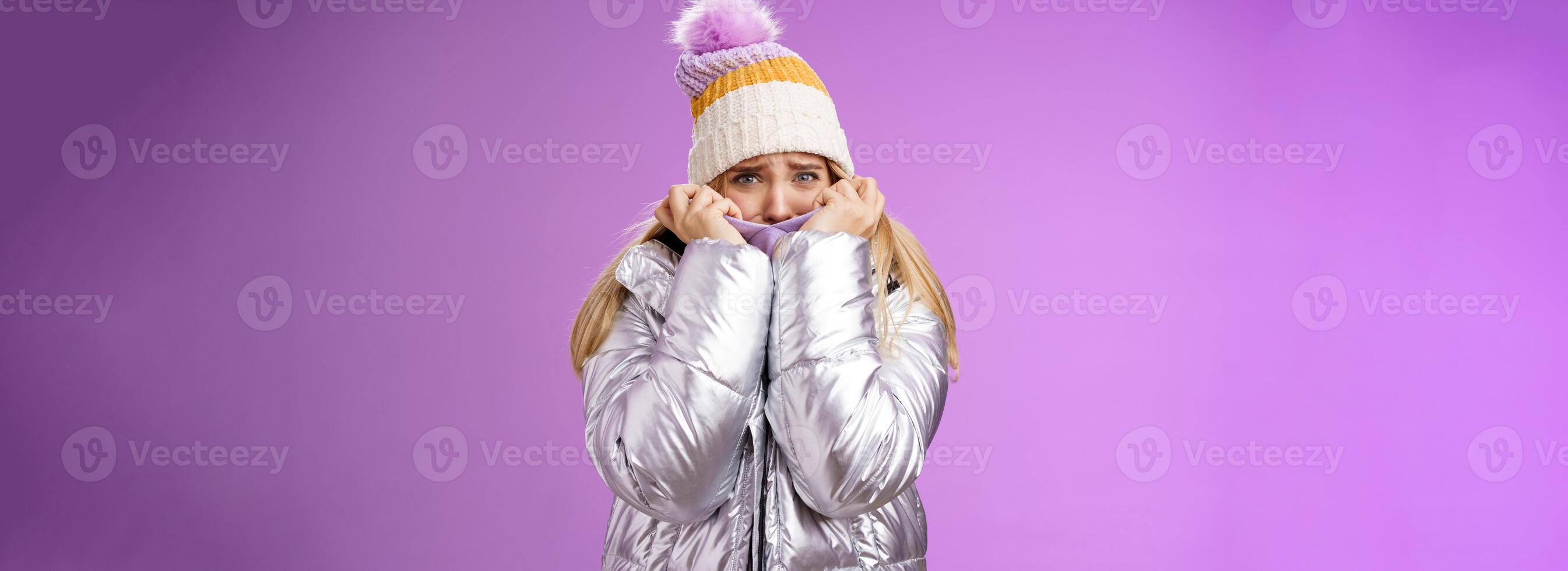 Scared afraid insecure coward girl in cute hat glittering shiny jacket pull cloth face frightened frowning stooping look concerned terrified scared death, standing purple background timid photo