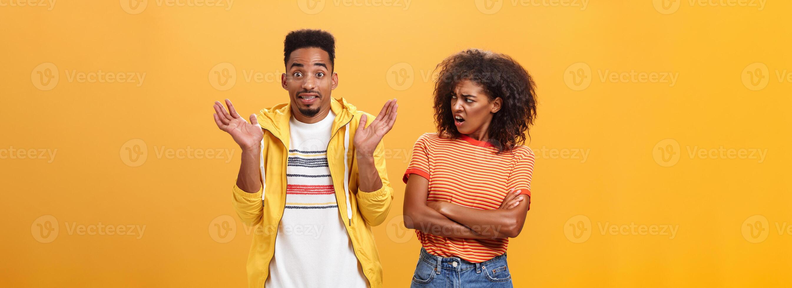 Jeez man what your problem. Offended displeased african american stylish and attractive girlfriend looking at boyfriend acting cool pretending he uninvolved shrugging with sorry look and smiling photo