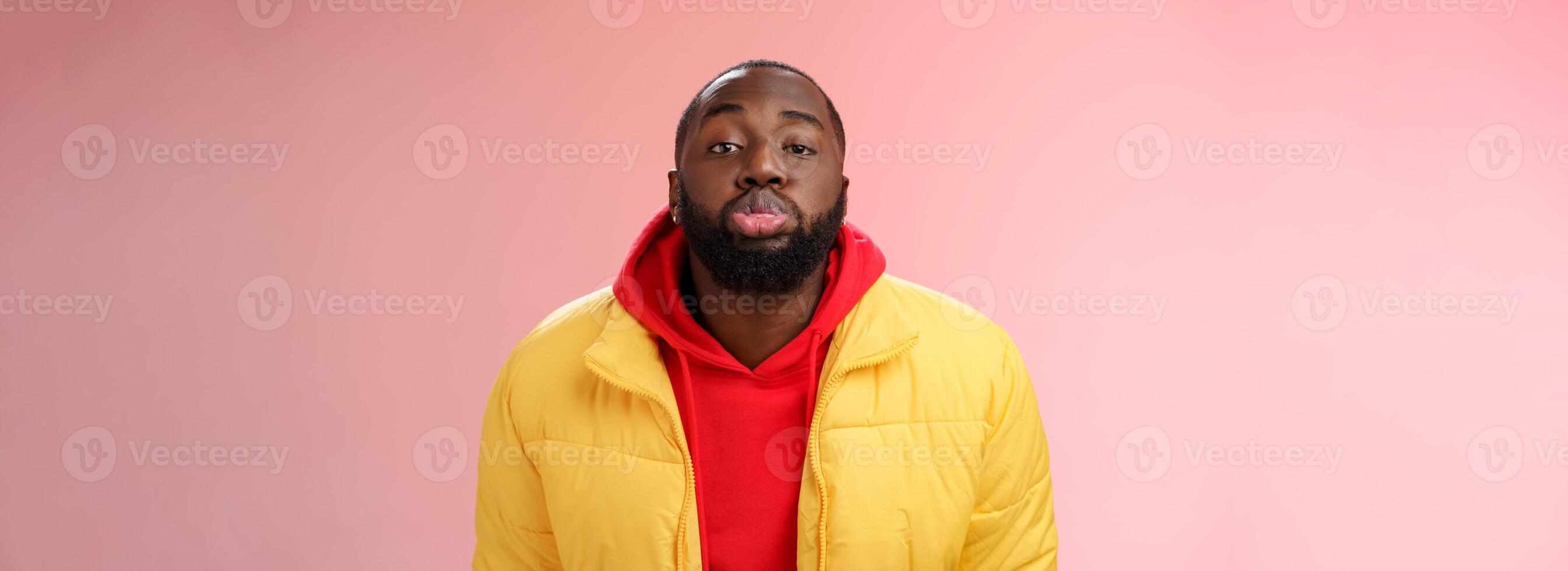 Portrait bored childish cute african bearded 25s male show tongue grimacing making funny faces immature behaviour unwilling grow-up standing pink background mimicking folding lips tube photo