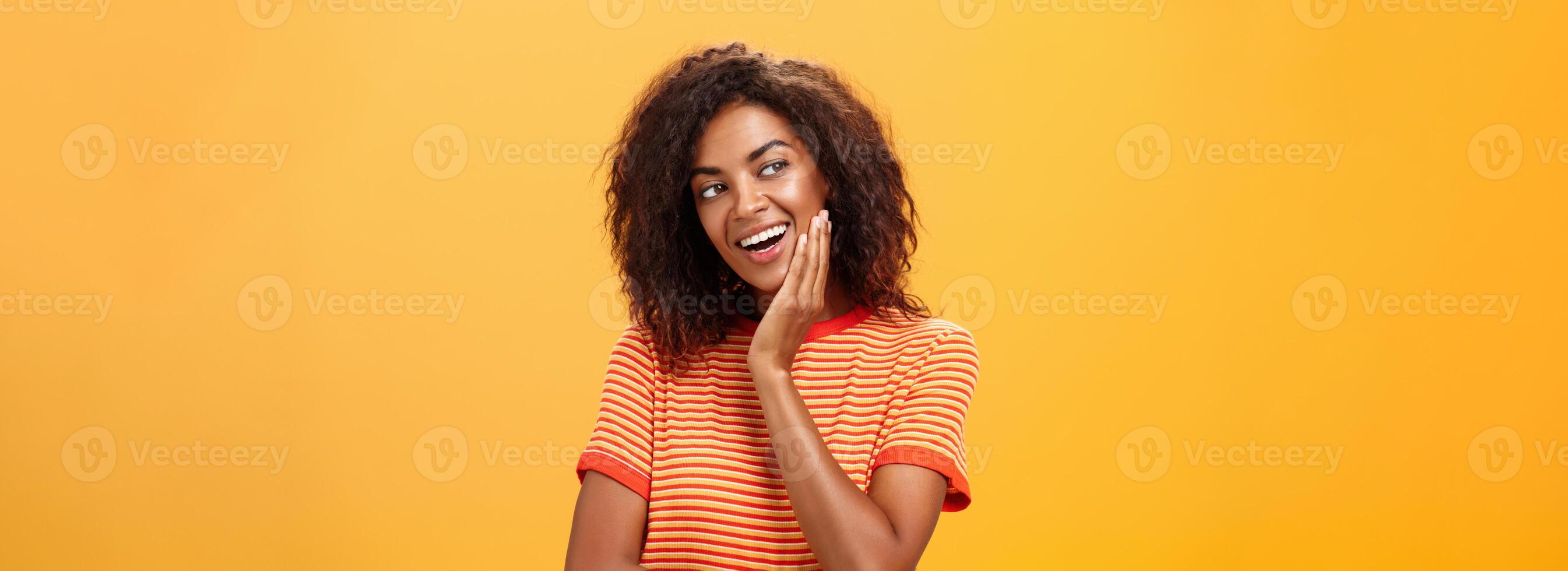 Cute creative and feminine stylish african american young female in striped t-shirt leaning head on palm gazing left with curious and adorable expression delightfully listening interesting story photo