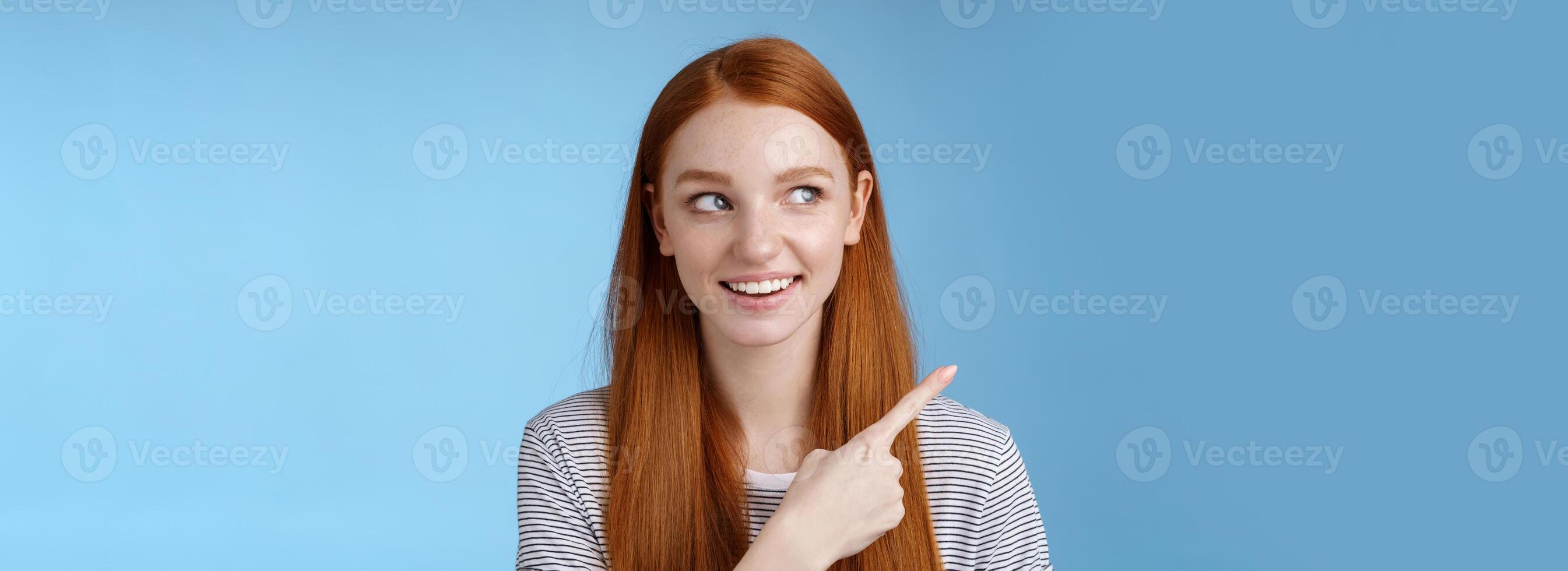Intrigued good-looking redhead joyful curious girl watching looking upper left corner interested smiling broadly visit cool amusing place explore travelling new country astonished, blue background photo