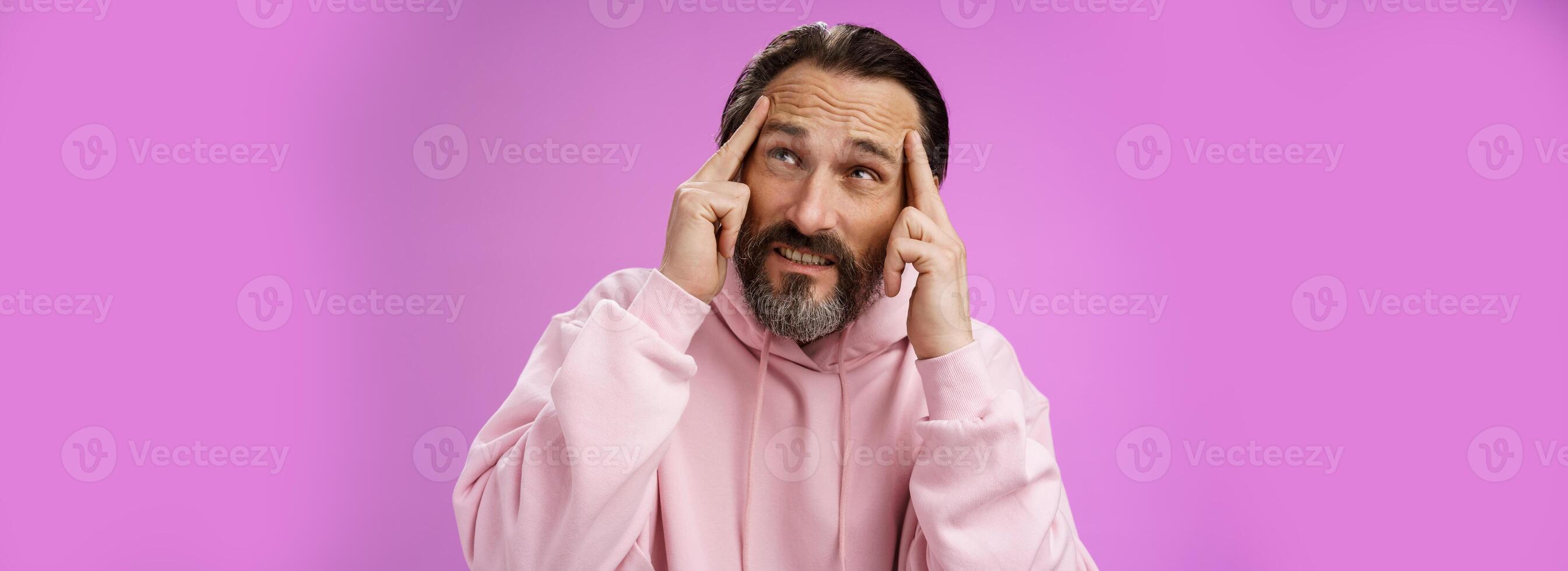 Worried intense disturbed mature male writer cannot create idea standing pressured touch forehead frowning look up problem concentrate not focused, standing purple background upset distracted photo