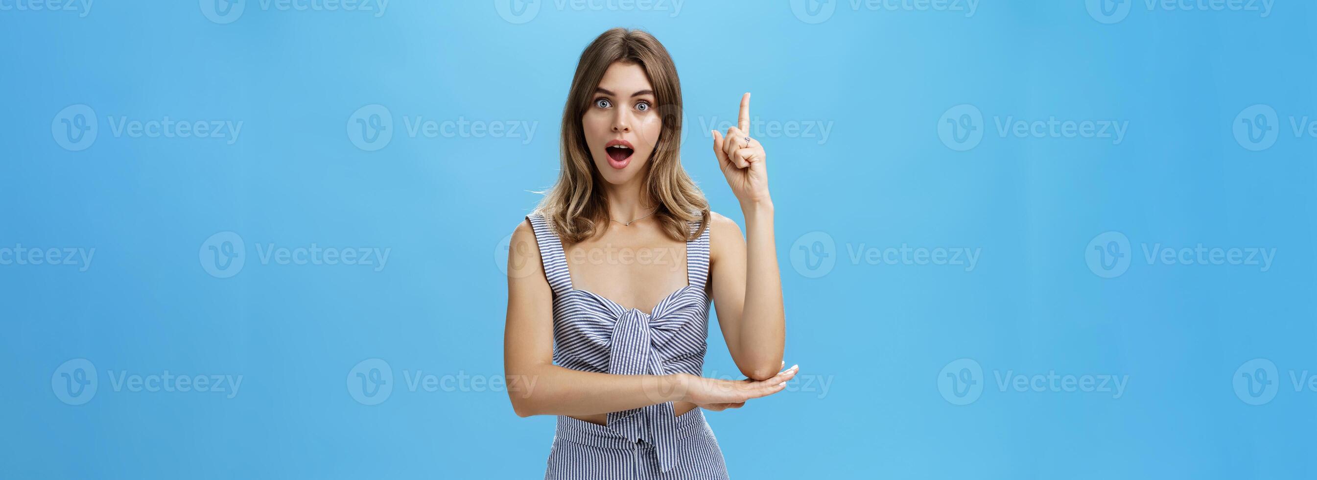 I got excellent idea. Portrait of polite adult straight A student raising index finger in eureka gesture wanting add suggestion asking permission to speak standing excited over blue background photo