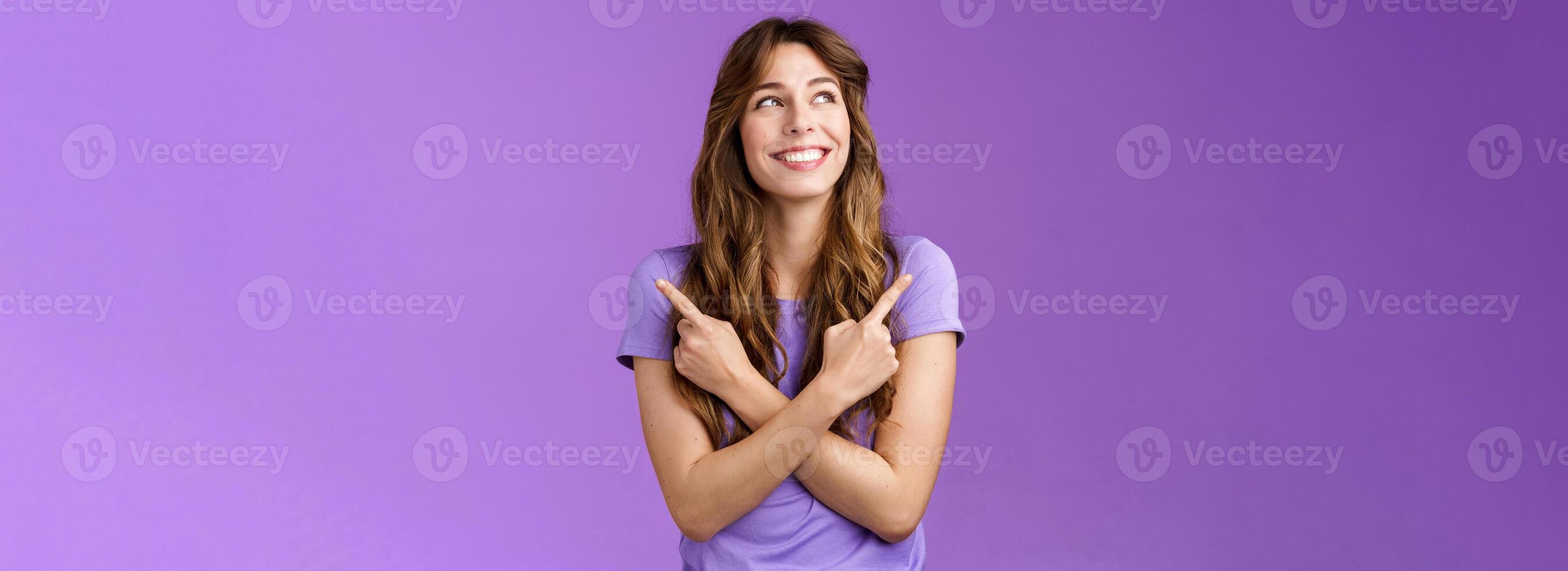 Cute tender feminine lovely curly-haired girl carefree deciding what country visit summer holiday smiling broadly making choice relaxed deciding between two variants pointing sideways look left photo