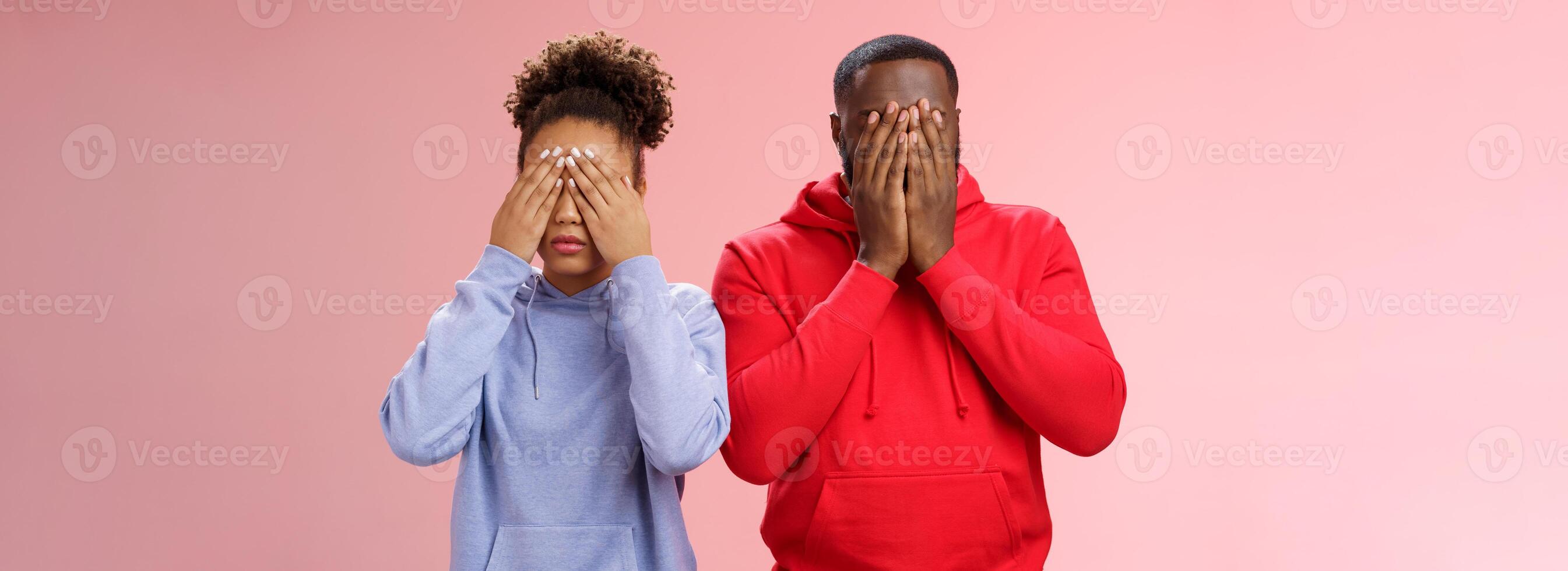 Two african-american man woman standing pink background hide faces close eyes palms tired looking lies upset waiting sign command see, playing hide-n-seek, unwilling spot personal problems photo