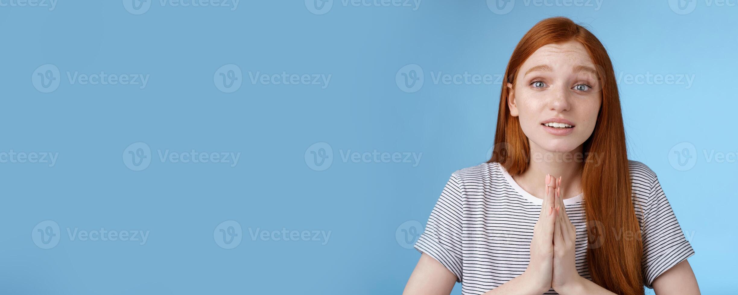 Cute european redhead girl blue eyes straight long ginger hairstyle making promise begging you help press palms together praying say please telling need favour worried pleading, blue background photo