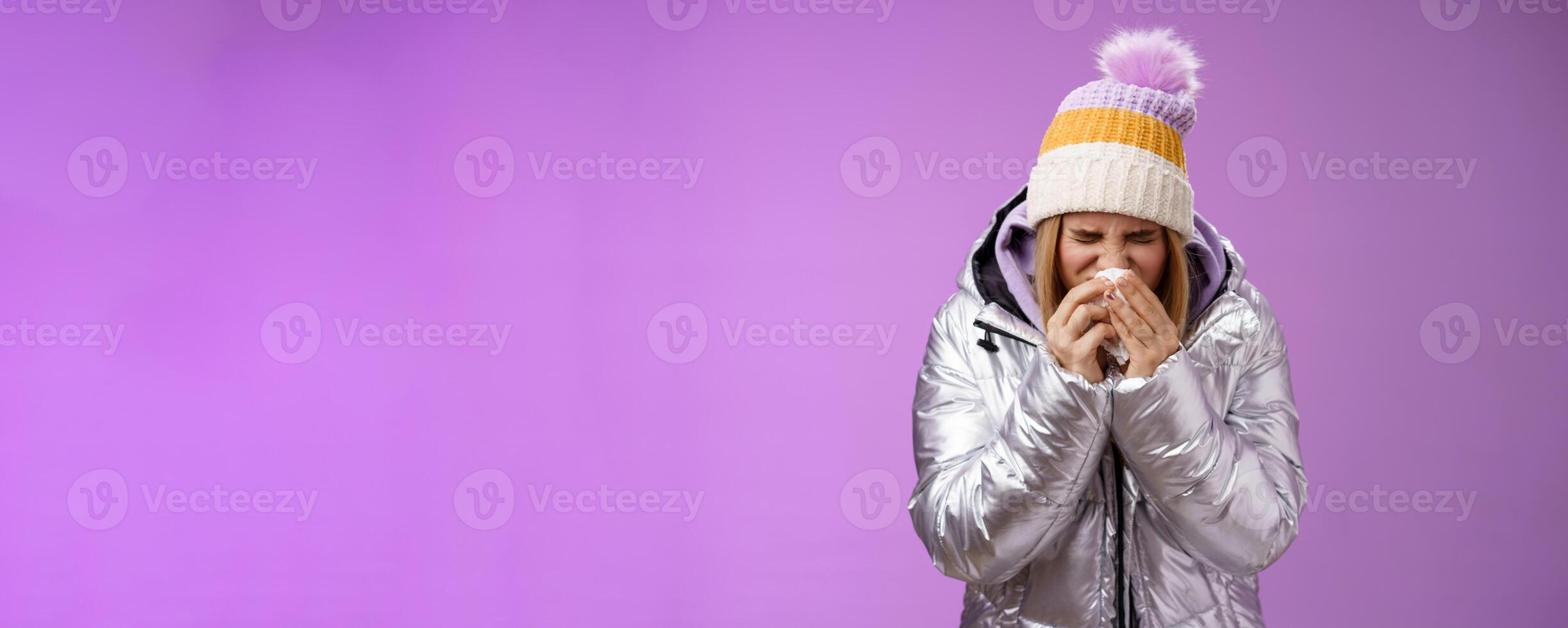 Girl runny nose sneeze tissue press napkin face got ill feeling unwell sick heading hospital standing purple background bending wearing silver stylish jacket winter hat, crying sobbing photo
