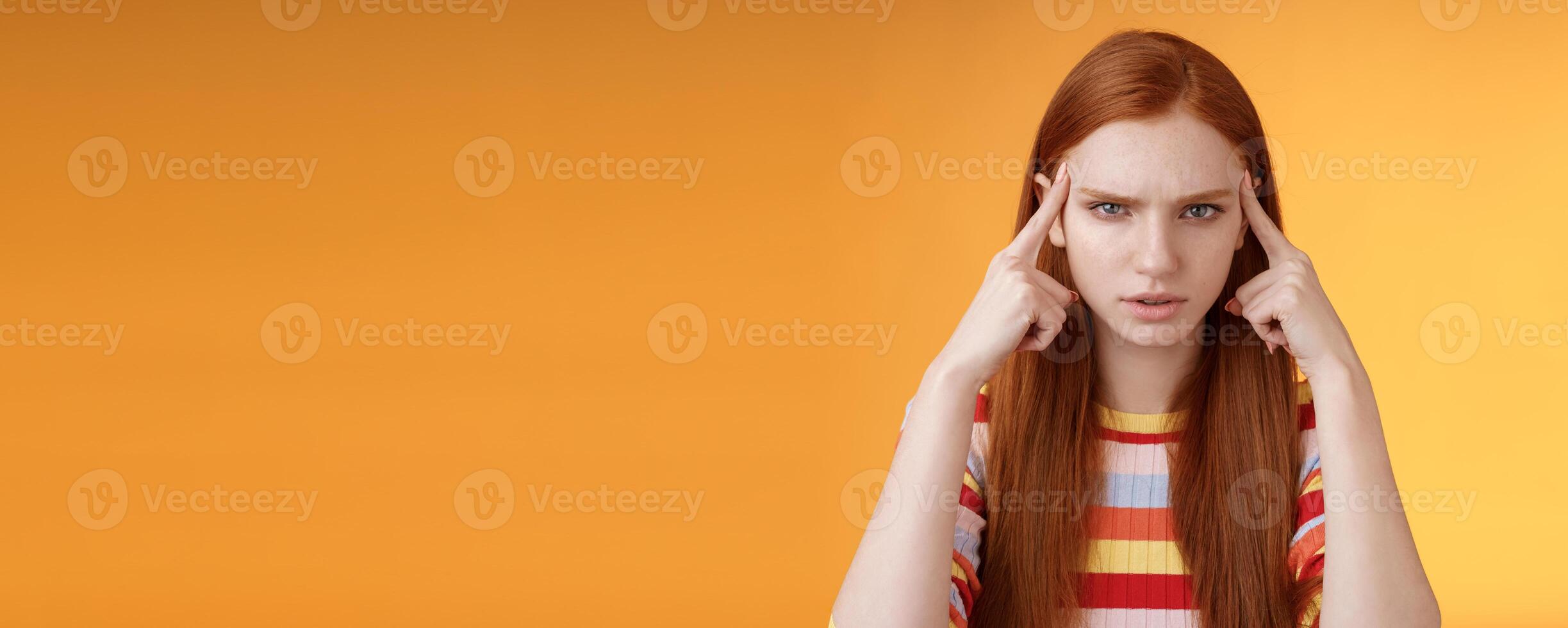 Puzzled serious-looking stressed-out young tired female student frowning look unhappy touching temples thinking trying focus, concentrate attention lecture memorizing hometask, orange background photo