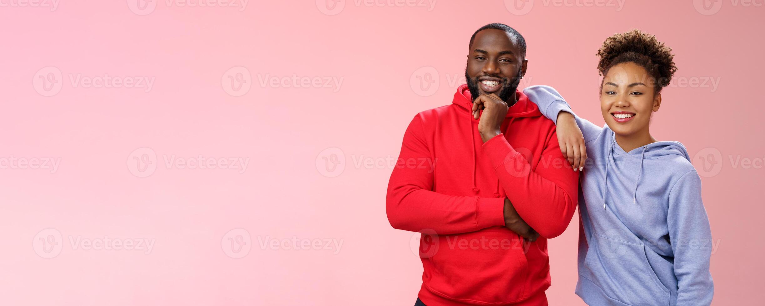 Romantic couple best friends standing pink background girl leaning boyfriend shoulder smiling broadly feel love respect each other working team standing pleased delighted friendly look camera photo