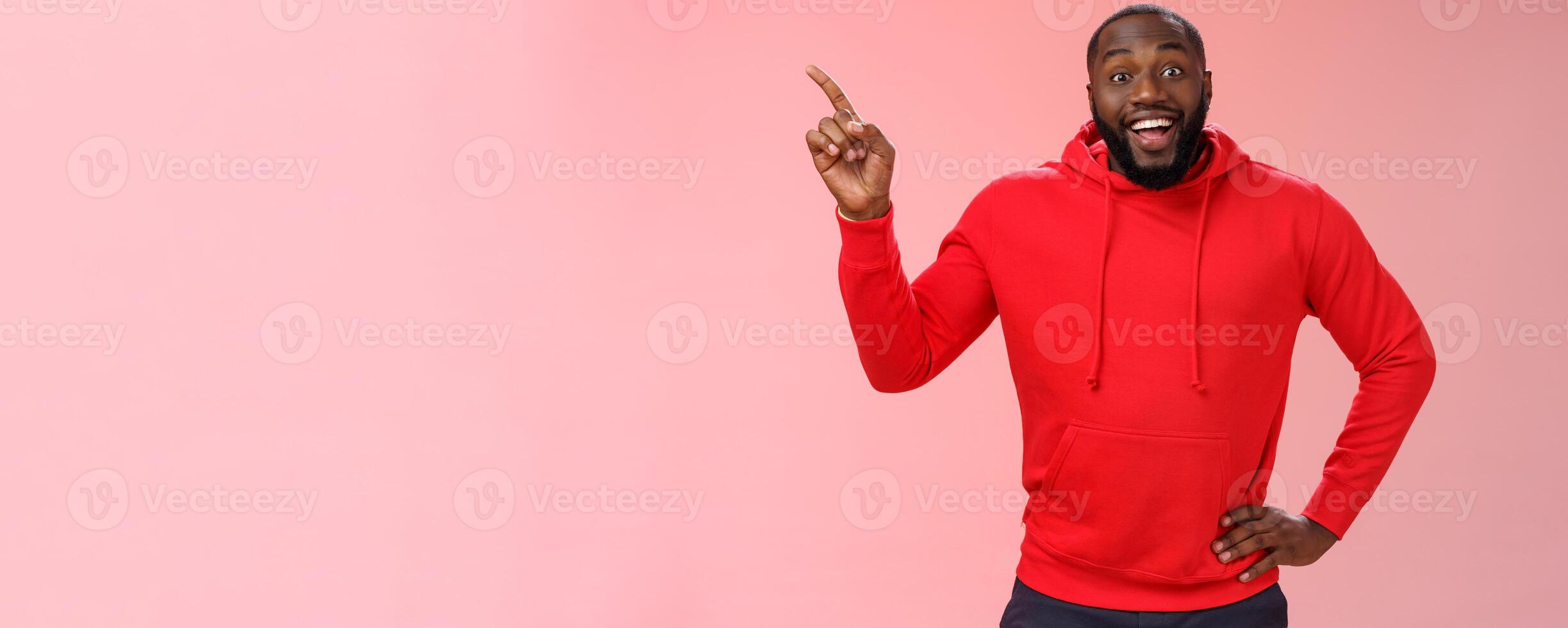 Enthusiastic happy good-looking young black guy beard pointing upper left corner smiling approval like curious about interesting item sale ask question excited impressed, standing pink background photo